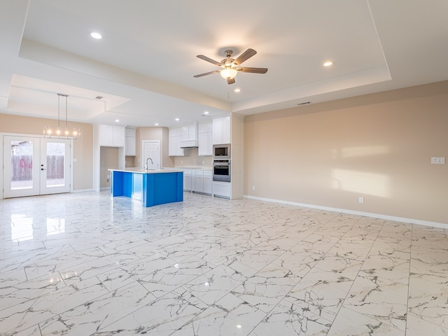 unfurnished living room featuring a raised ceiling, french doors, sink, and ceiling fan