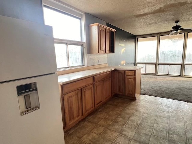 kitchen featuring kitchen peninsula, a textured ceiling, light colored carpet, ceiling fan, and white fridge