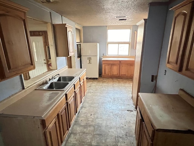 kitchen with sink, a textured ceiling, and white refrigerator