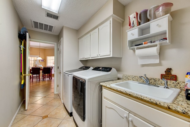 5500 Heartland Ct, Midland, TX 79707 - laundry room with washing machine and clothes dryer, cabinet space, light tile patterned floors, and a textured ceiling