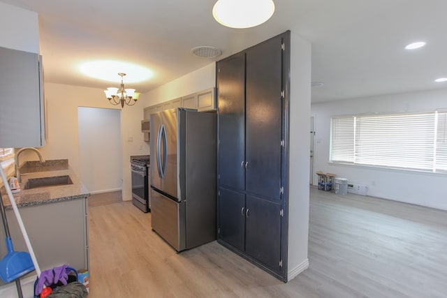 kitchen featuring light stone countertops, sink, an inviting chandelier, light hardwood / wood-style floors, and appliances with stainless steel finishes