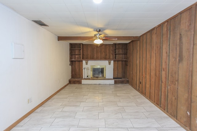 unfurnished living room with wooden walls, a fireplace, and ceiling fan