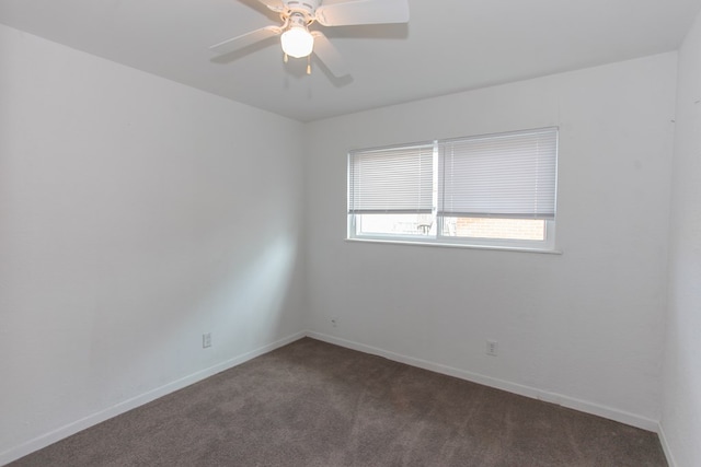 spare room featuring dark colored carpet and ceiling fan