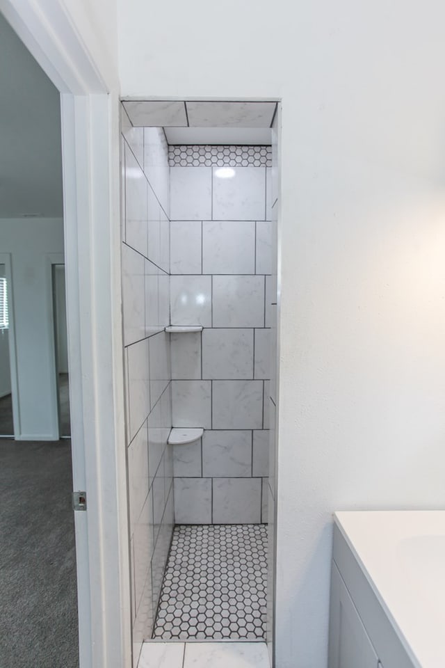 bathroom with a tile shower and vanity