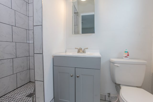 bathroom with tiled shower, vanity, and toilet