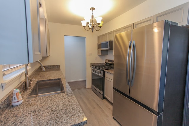 kitchen featuring an inviting chandelier, sink, hanging light fixtures, light wood-type flooring, and stainless steel appliances