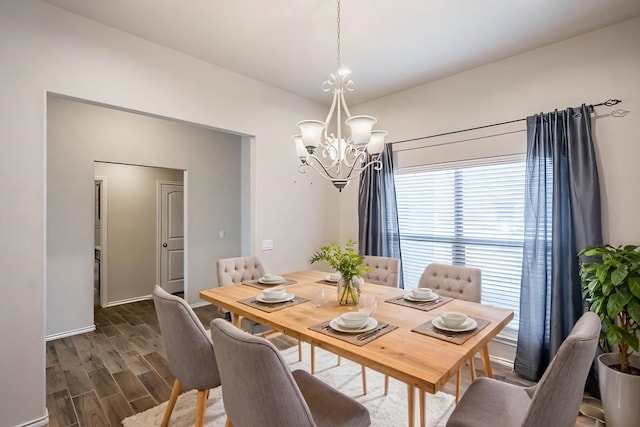 dining area with vaulted ceiling, dark wood-type flooring, and a notable chandelier