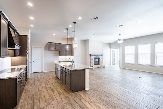 kitchen with visible vents, decorative backsplash, light wood-style floors, a sink, and dark brown cabinets