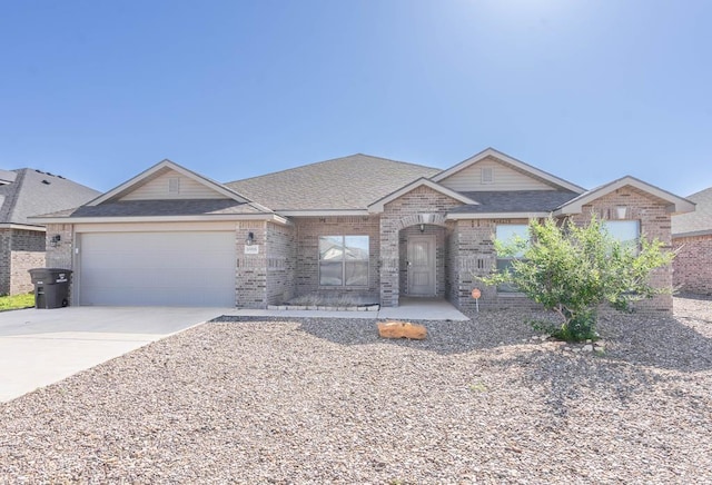 ranch-style house with a garage, brick siding, driveway, and roof with shingles