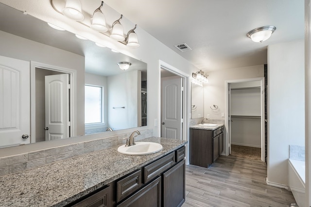 full bathroom featuring wood finished floors, two vanities, a sink, and visible vents