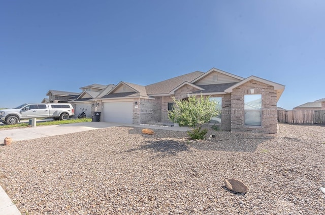 view of front of home featuring driveway, a garage, fence, and brick siding