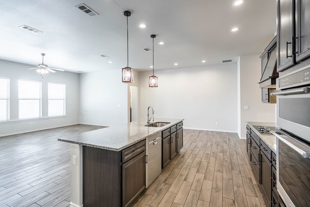 kitchen featuring appliances with stainless steel finishes, visible vents, a sink, and light wood-style flooring