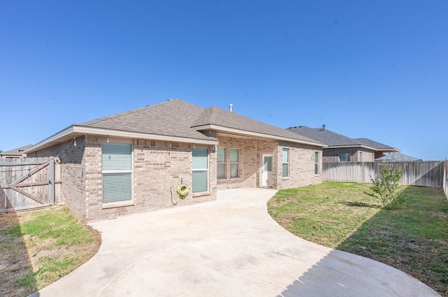 back of house with a fenced backyard, brick siding, a shingled roof, a yard, and a patio area