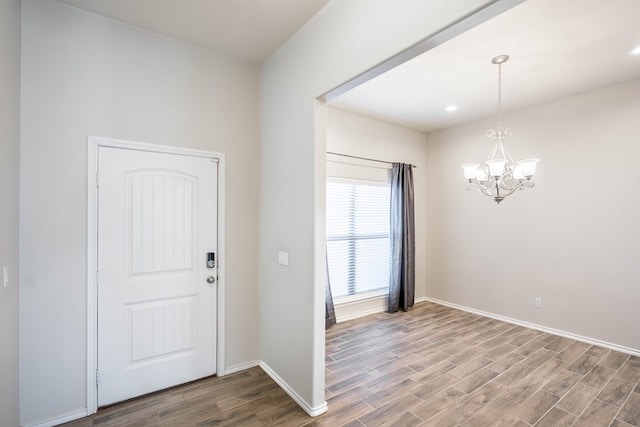 entryway with baseboards, wood finished floors, and a notable chandelier