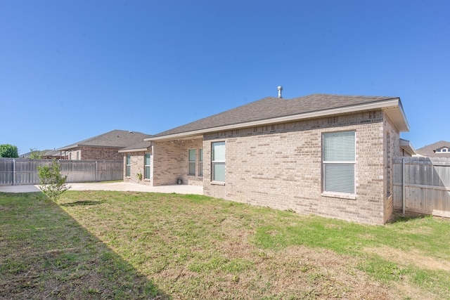 back of property with a yard, a patio, brick siding, and a fenced backyard