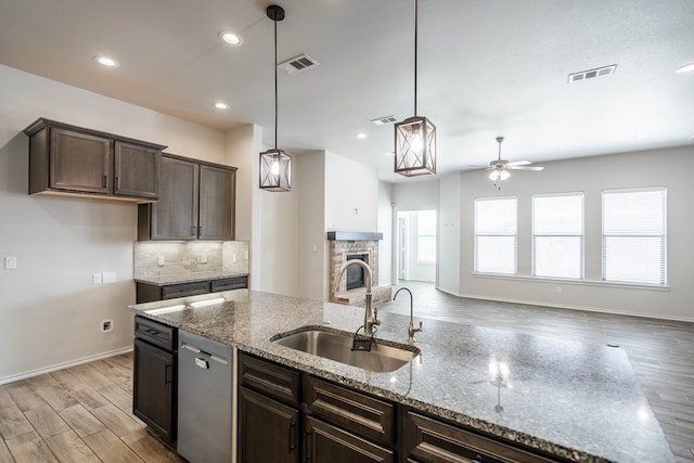 kitchen featuring dark brown cabinetry, light wood finished floors, visible vents, a sink, and stainless steel dishwasher