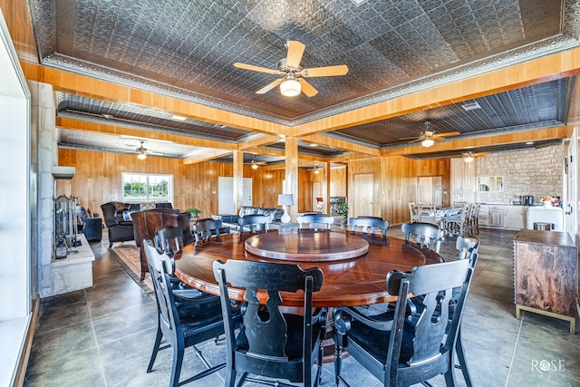 dining room featuring beamed ceiling, ornamental molding, and wood walls