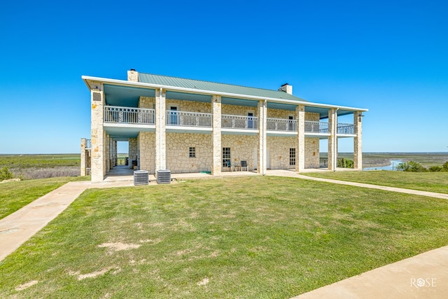 exterior space featuring a lawn, a balcony, a water view, and a patio