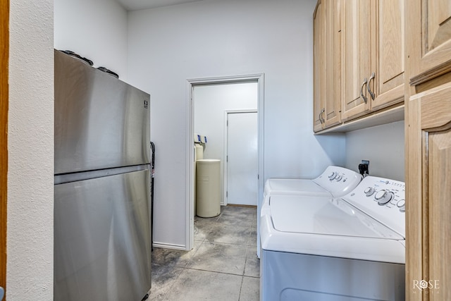 laundry area featuring cabinets, light tile patterned floors, and washing machine and clothes dryer