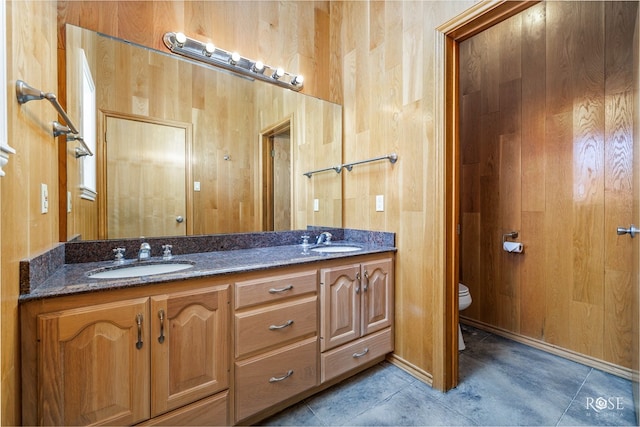 bathroom with tile patterned flooring, vanity, toilet, and wood walls