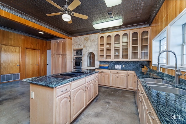 kitchen with wood walls, sink, ceiling fan, a kitchen island, and stainless steel appliances