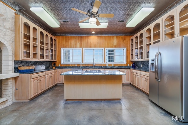 kitchen featuring ceiling fan, a center island, stainless steel appliances, a brick fireplace, and light brown cabinetry