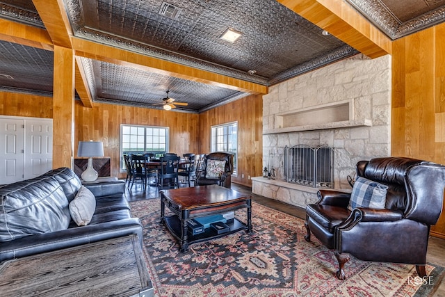 living room with ceiling fan, crown molding, wooden walls, wood-type flooring, and beam ceiling