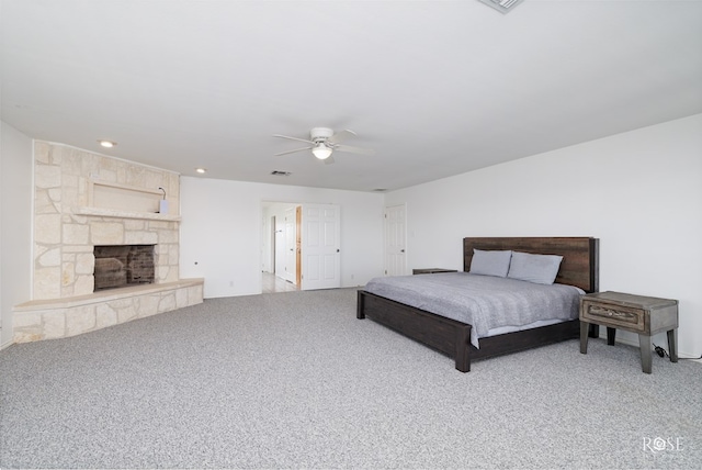 bedroom featuring carpet flooring, a stone fireplace, and ceiling fan