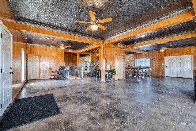 misc room featuring ceiling fan, wood walls, ornamental molding, and beam ceiling