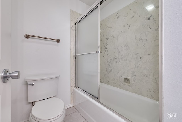 bathroom featuring tile patterned flooring, toilet, and shower / bath combination with glass door