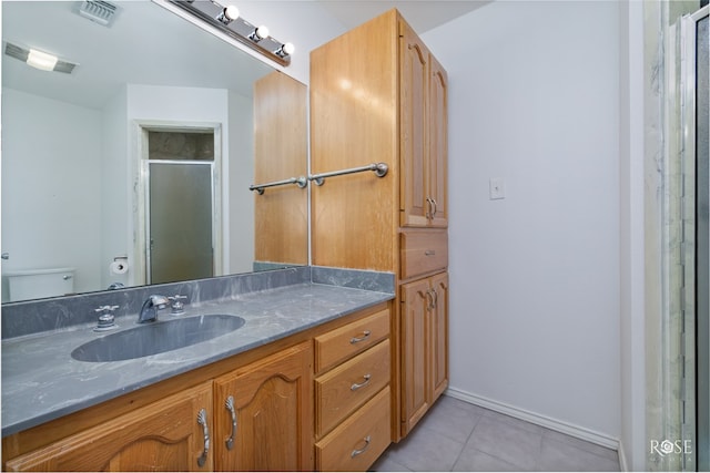 bathroom featuring tile patterned flooring, vanity, toilet, and an enclosed shower