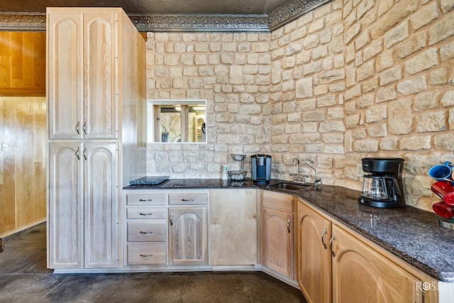 kitchen with light brown cabinets, dark stone countertops, and sink