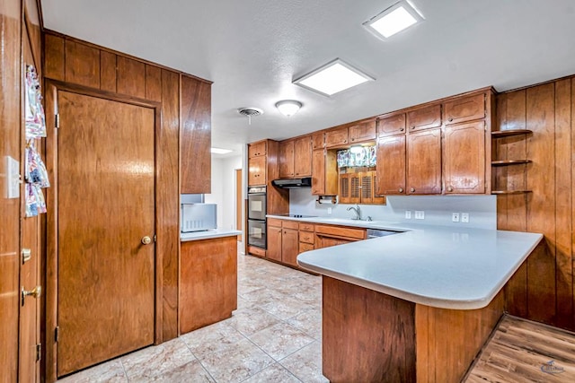 2310 W Shandon Ave, Midland, TX 79705 - kitchen featuring brown cabinetry, light countertops, a peninsula, open shelves, and black electric stovetop