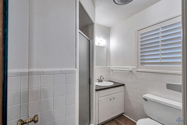 2310 W Shandon Ave, Midland, TX 79705 - full bathroom featuring tile walls, toilet, vanity, a stall shower, and a wainscoted wall