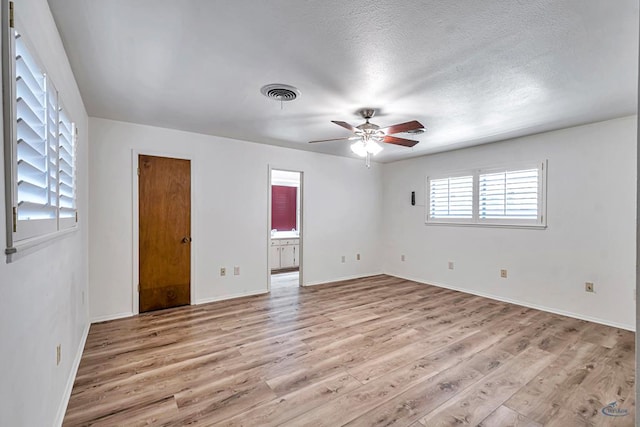 2310 W Shandon Ave, Midland, TX 79705 - unfurnished bedroom featuring light wood-style floors, baseboards, ensuite bathroom, and a textured ceiling