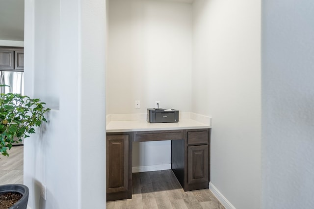 bar with light hardwood / wood-style flooring and dark brown cabinets