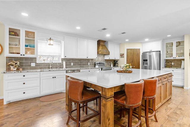 6413 Piedmont Dr, Odessa, TX 79762 - kitchen with stainless steel appliances, custom exhaust hood, a center island, tasteful backsplash, and a breakfast bar