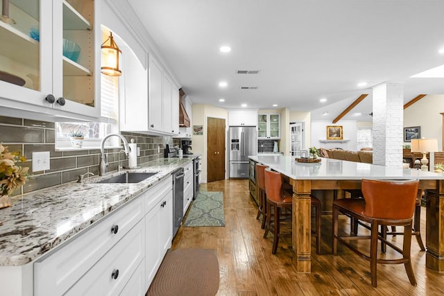 6413 Piedmont Dr, Odessa, TX 79762 - kitchen with appliances with stainless steel finishes, decorative columns, hardwood / wood-style floors, decorative backsplash, and a spacious island