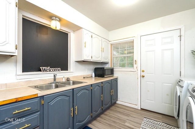 kitchen with light hardwood / wood-style flooring, white cabinetry, washer and clothes dryer, and sink