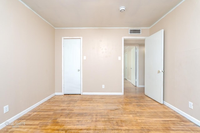 spare room with light wood-type flooring and crown molding