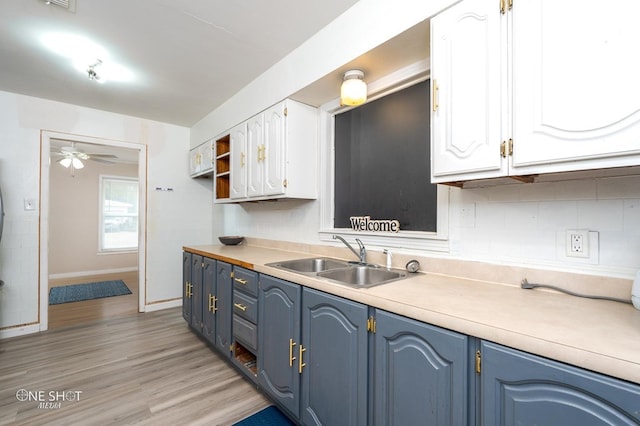 kitchen featuring blue cabinets, sink, light hardwood / wood-style flooring, ceiling fan, and white cabinetry