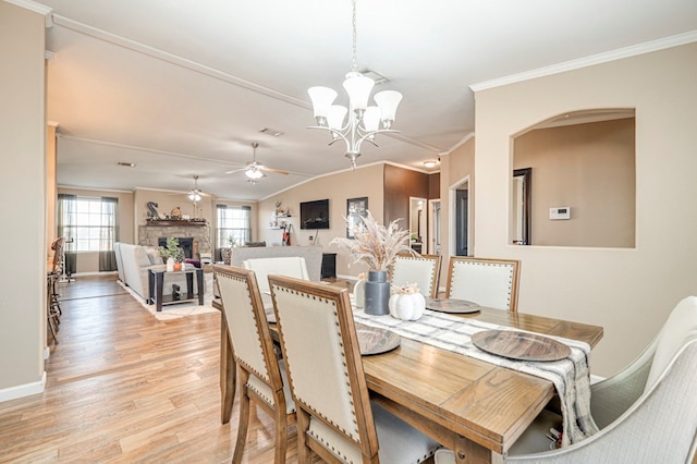 dining space featuring ceiling fan with notable chandelier, light hardwood / wood-style floors, vaulted ceiling, and ornamental molding