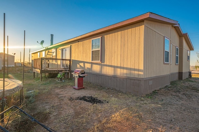 property exterior at dusk featuring a deck and a trampoline