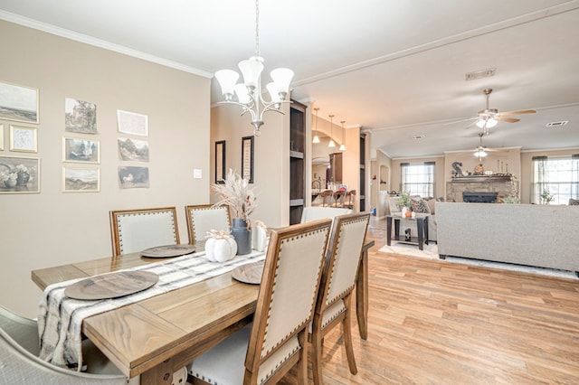 dining space with ceiling fan with notable chandelier, light hardwood / wood-style flooring, plenty of natural light, and crown molding