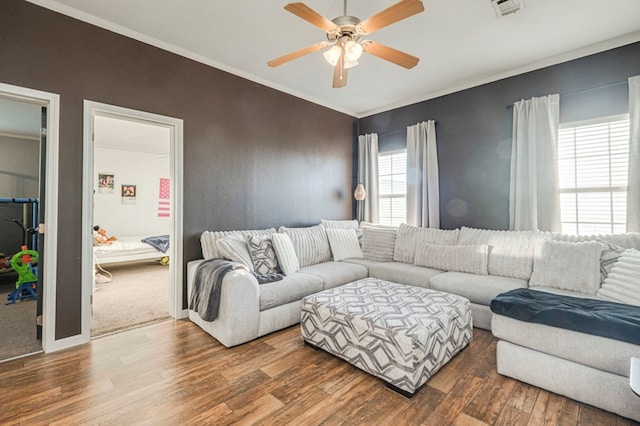 living room featuring plenty of natural light, ceiling fan, crown molding, and dark wood-type flooring