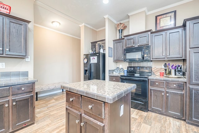 kitchen featuring dark brown cabinetry, crown molding, light hardwood / wood-style floors, a kitchen island, and black appliances