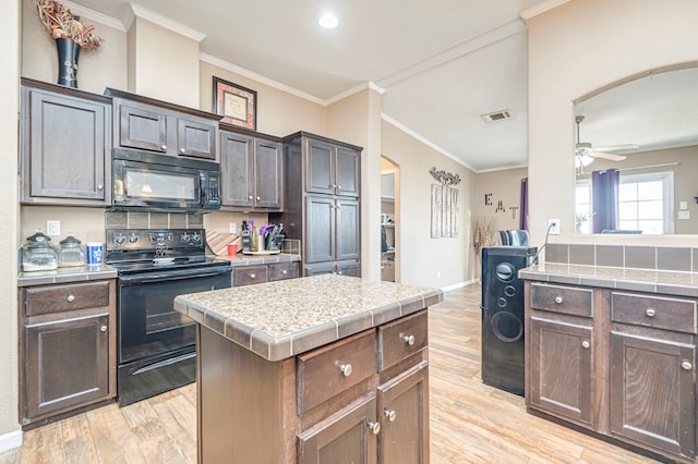 kitchen featuring light wood-type flooring, dark brown cabinetry, ceiling fan, black appliances, and a center island