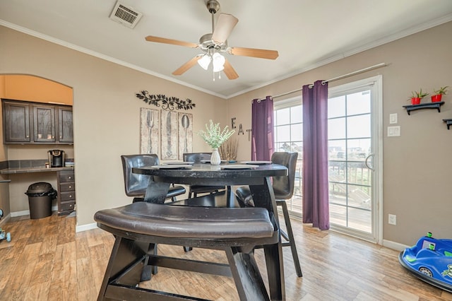 dining room with ceiling fan, light wood-type flooring, and crown molding