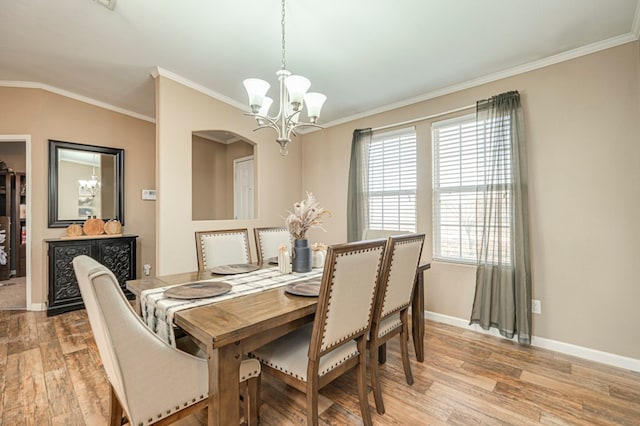 dining space featuring an inviting chandelier, ornamental molding, and light hardwood / wood-style flooring