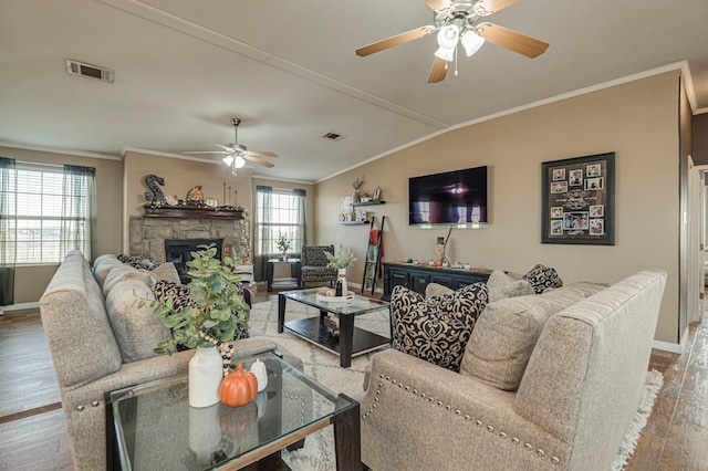 living room with hardwood / wood-style flooring, a healthy amount of sunlight, crown molding, and a fireplace